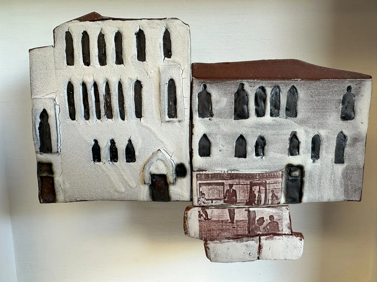 Cream and grey ceramic buildings with pointed windows and rust-coloured printed details