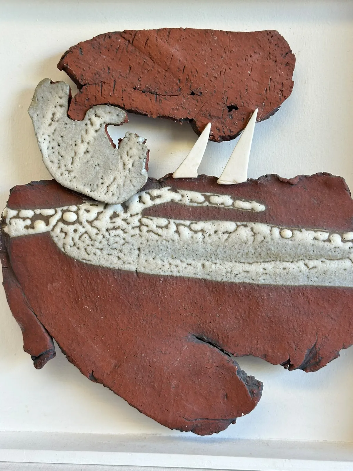 Rust-coloured ceramic wall piece with cream textured waves and two white sails